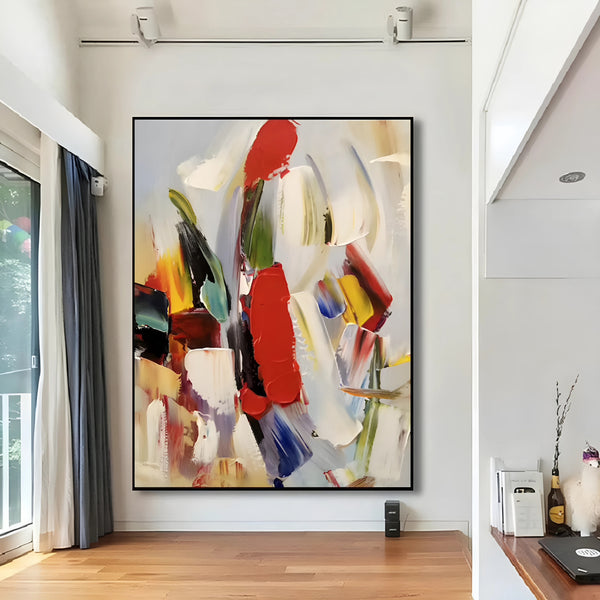 Colorful abstract artwork featuring vivid splashes of red, yellow, blue, and green, mounted on a clean white wall in a contemporary art gallery.