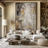 Large abstract painting with textured gray, gold, and white brushstrokes, elegantly framed and displayed in a modern living room.