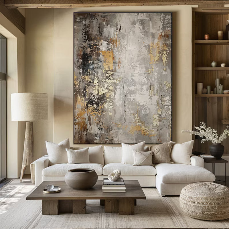 Large abstract painting with textured gray, gold, and white brushstrokes, elegantly framed and displayed in a modern living room.