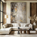 Contemporary abstract artwork featuring gold and silver hues on a textured canvas, enhancing the warm aesthetic of a rustic yet modern space.