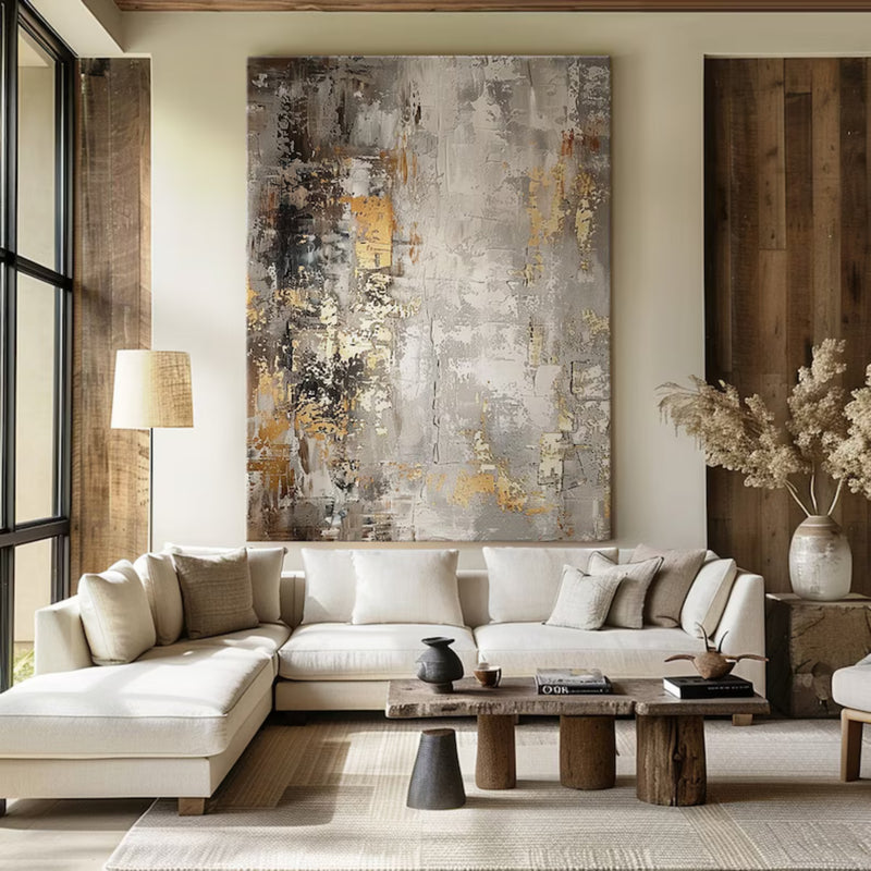 Contemporary abstract artwork featuring gold and silver hues on a textured canvas, enhancing the warm aesthetic of a rustic yet modern space.