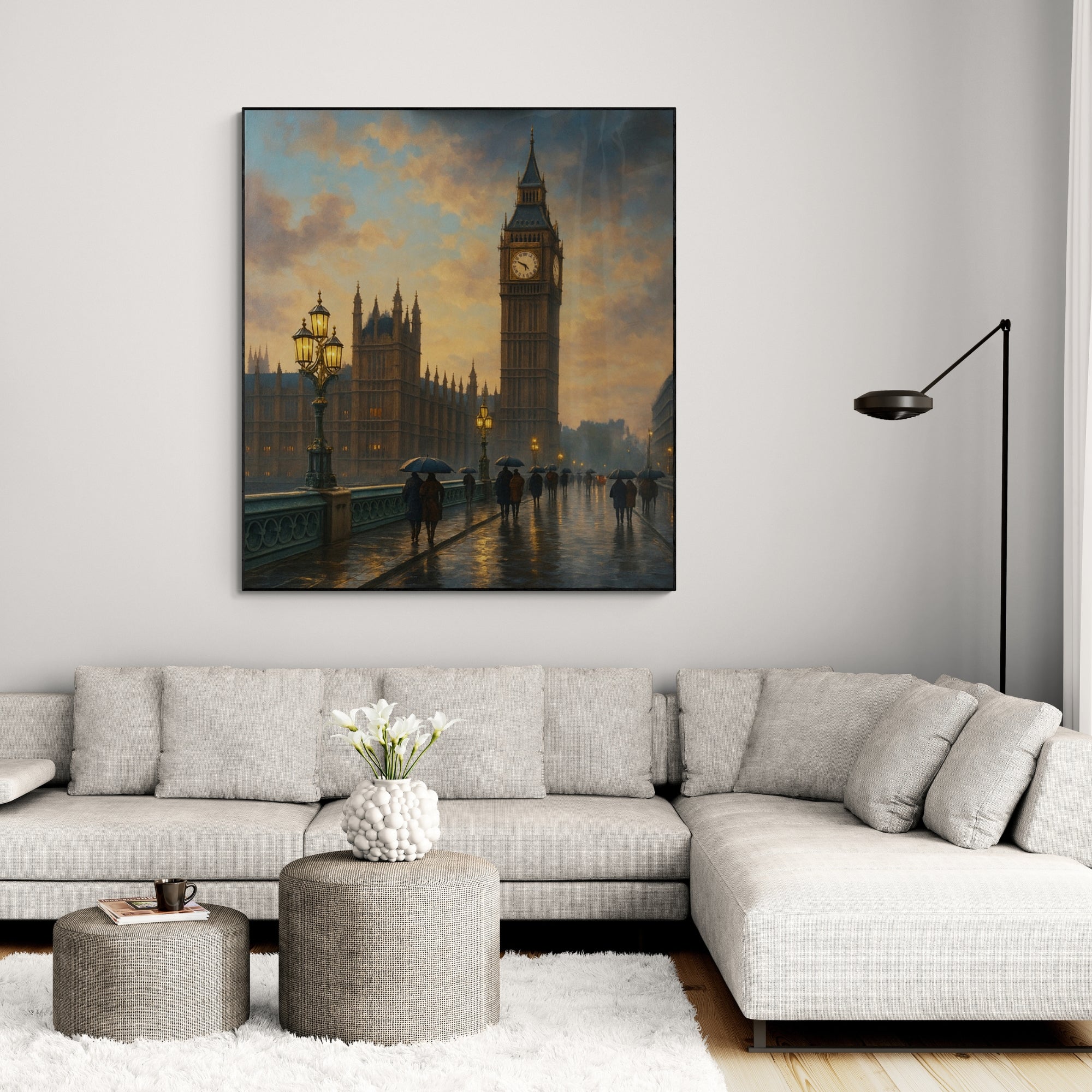 A framed oil painting of Big Ben and the Houses of Parliament in London, displayed on a wall above a modern gray sofa and a round gray table with a vase of flowers on it.