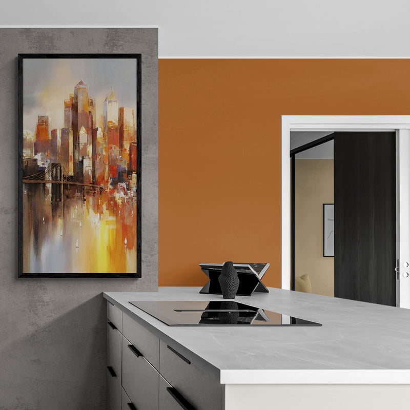 Framed abstract skyline artwork with rich oranges, yellows, and greys, hung above a sleek kitchen counter, creating a bold contemporary contrast.